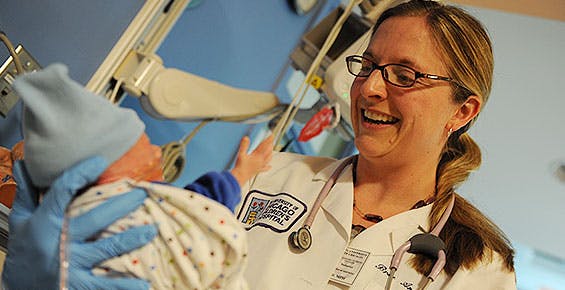 Neonatologist Bree Andrews, MD, cradling a baby boy in the NICU